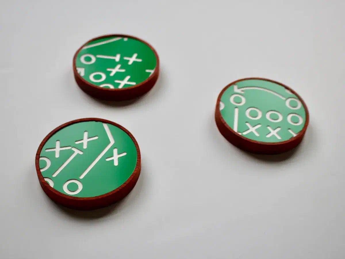 Green acrylic football-play designs fitted into reddish wooden coasters