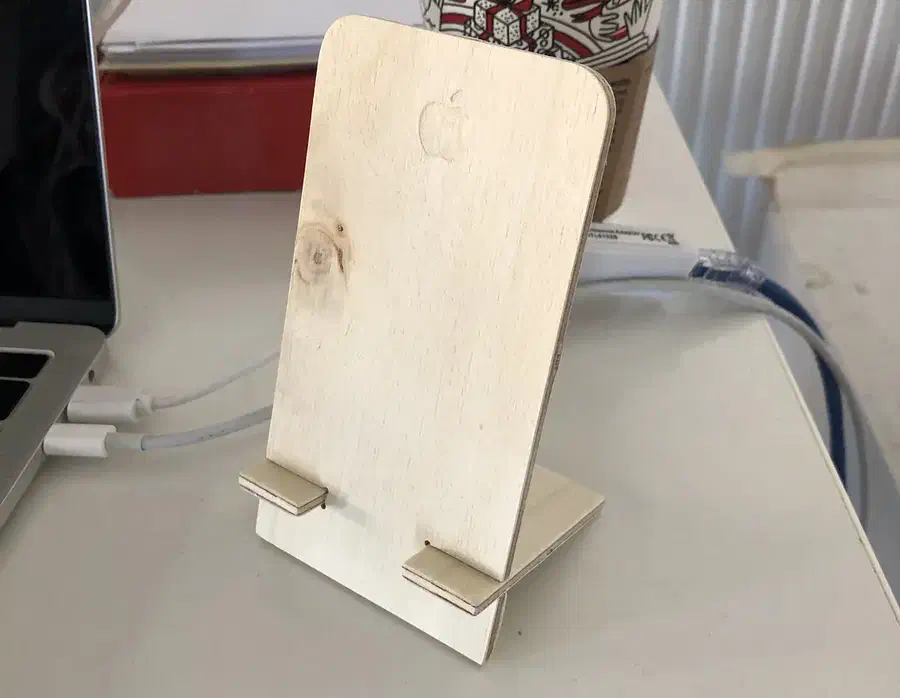 Two-piece plywood phone stand with a tall rounded back and a slotted support