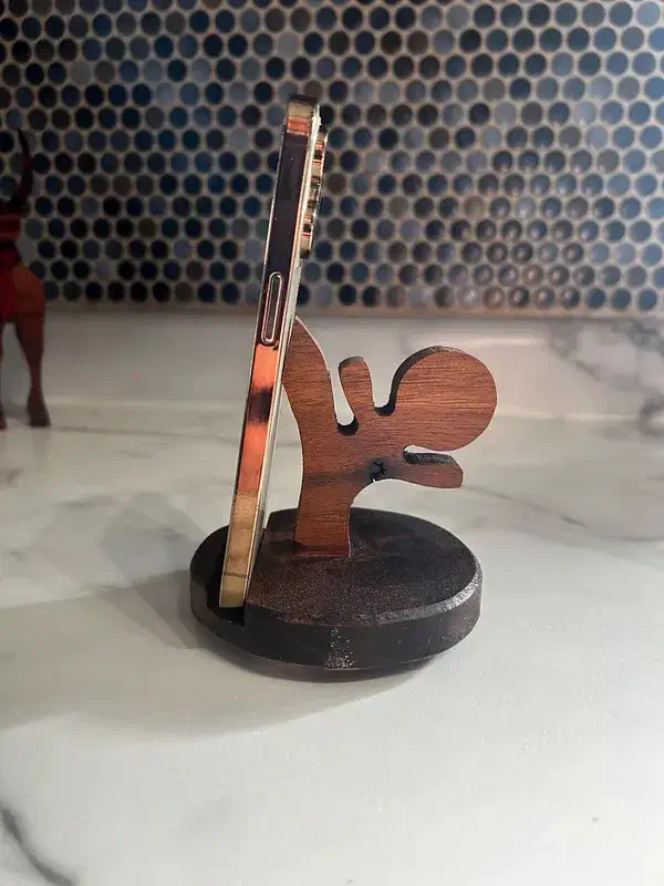 Wooden ninja silhouette supporting a phone on a round dark base