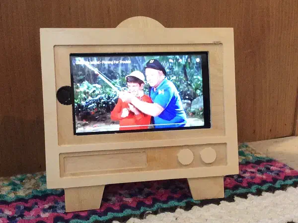 Finished plywood television-shaped stand holding a phone horizontally