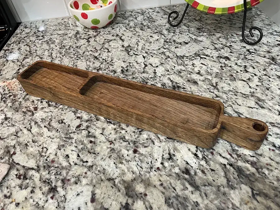 A long wooden tray with two recessed compartments and a handle