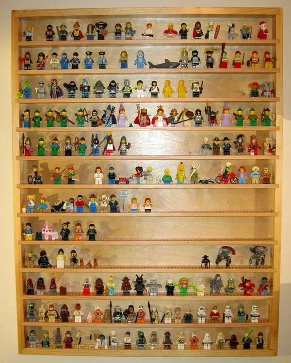 A tall wooden display case filled with LEGO minifigures on narrow pin strips